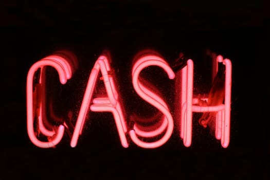 A Pink neon sign spelling out the words CASH. Set on a black background.