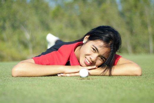Young, female golf player with ball, at the hole on green