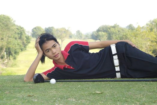 Young, female, Asian golf player resting at the tee-box