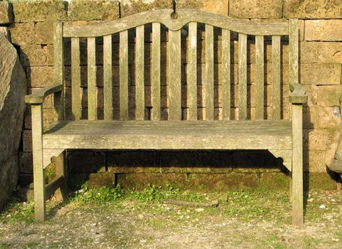 wooden garden bench in front of a stone wall