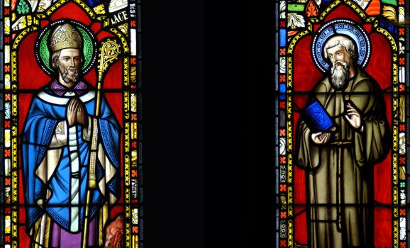 A pair of stained glass windows in the chapel on the Farne Islands, UK, depicting Saint Cuthbert as Bishop and hermit. Space for text between the images.