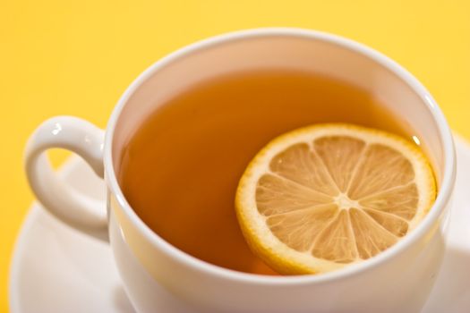 cup of tea with lemon over yellow