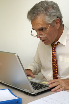 A businessman looking intently at his laptop computer. What is going on on the screen?
