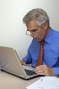 A businessman sits in front of his laptop computer, looking at the screen inmild surprise. Space for text on the white background.