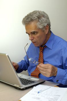 A businessman looks at his laptop computer as though it's about to explode. Something has gone seriously wrong.
