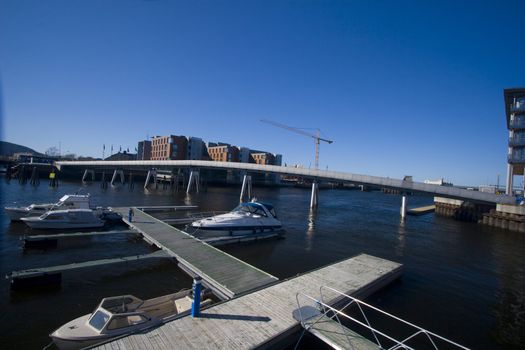 Illustration of city life by a river. With construction, hotels, luxury boats and offices. Solsiden in Trondheim, Norway. 