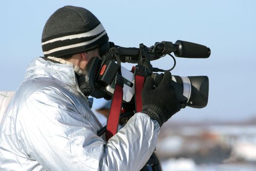 The journalist with a videocamera in the winter morning