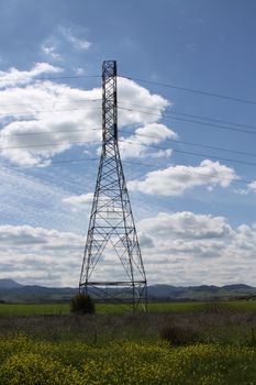 Electricity pylon on a hill over clear blue sky.