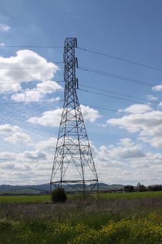 Electricity pylon on a hill over clear blue sky.