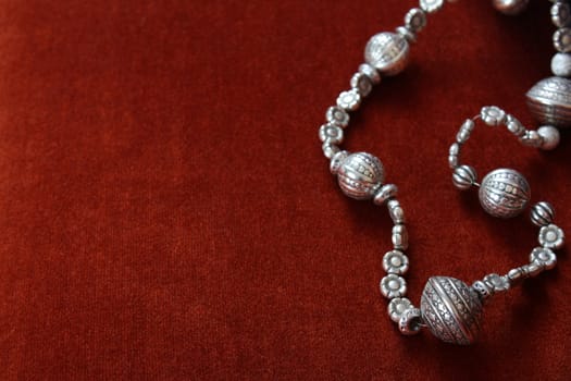 Silver bead necklace on an orange brown background