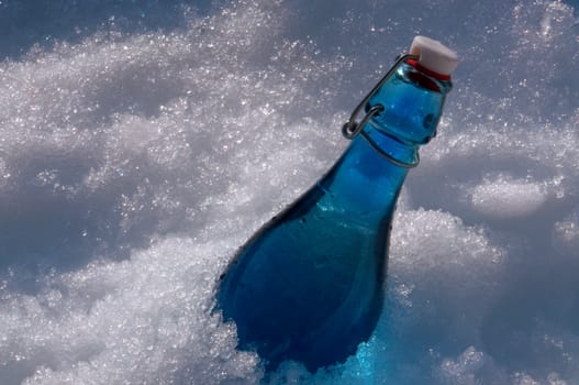 A turquoise bottle with water buried in snow