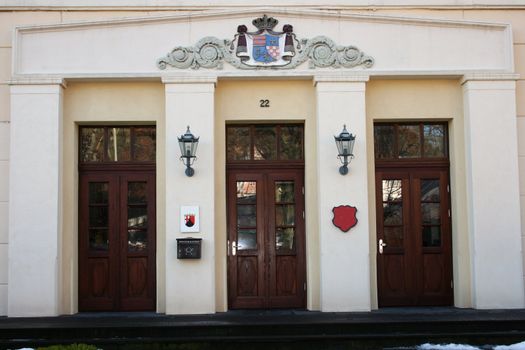 Historisches Gebäude mit drei hohen Holztüren und Stuckornamenten  	Historic building with three tall wooden doors and stucco ornaments