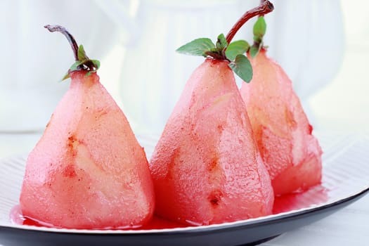 A group of three pears that have been poached in red wine sauce.

