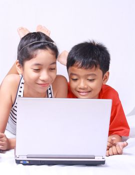 young asian kids enjoying and sharing a laptop computer