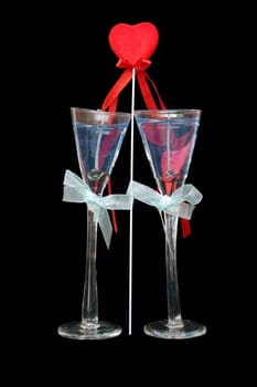 Candles in wine-glasses on a black background and red heart
