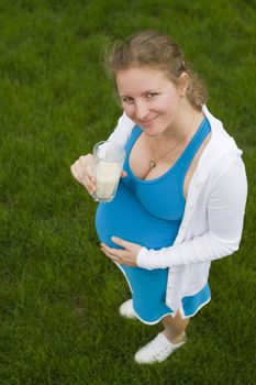 A helathy woman posing with a glass of milk in her blue outfit.