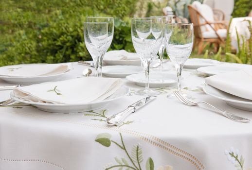 Table setting for garden banquet with expensive table cloth, silverware, and wine glasses