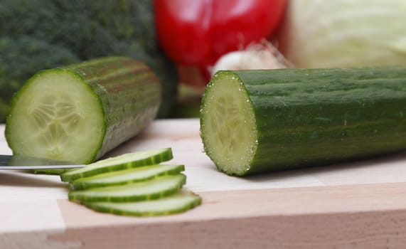 Close-up image of a sliced cucumber on a wooden choping board.Selective focus on the cucumber.