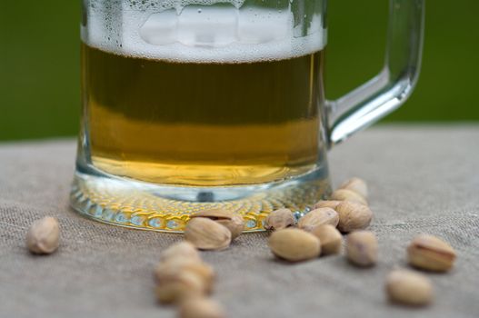 Mug with beer and pistachios. Macro.