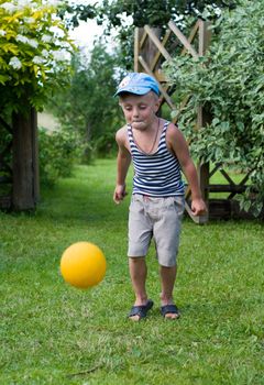 The little boy plays a ball on a grass