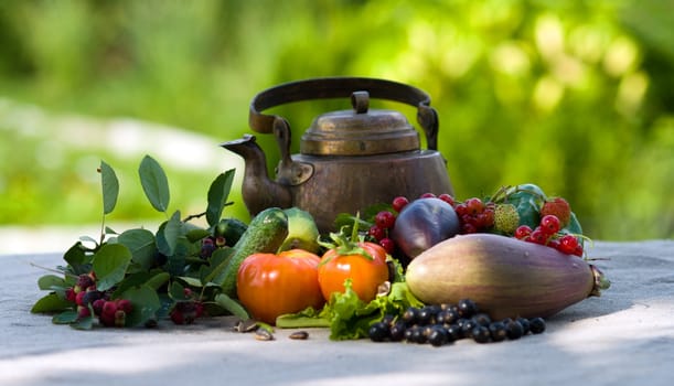 Berries, vegetables and an ancient teapot on a grey cloth