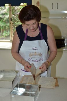 Checking the old hand written recipe book before preparing ingredients for the cake.