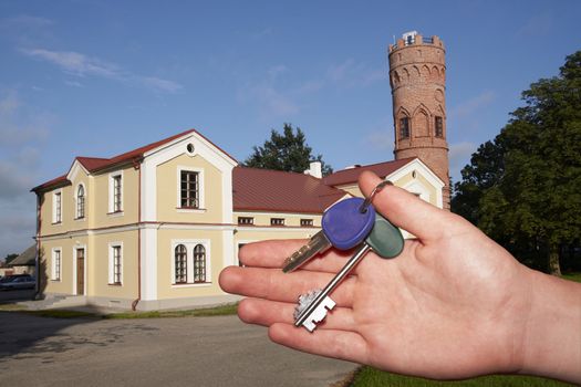 New house owner. Key in hand and new cottage on background.