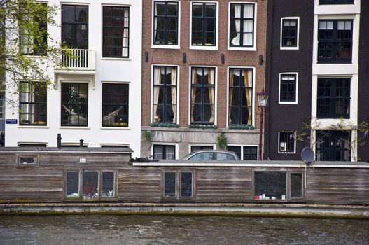 Dutch architecture. The barge is in the channel against the backdrop of the Amsterdam houses. Frontally. Fragment.