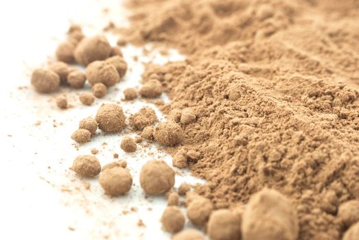 Macro (close-up) of cocoa powder, scattered on a white surface.