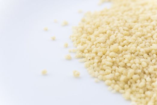 Macro (close-up) of couscous grain scattered on right side of frame.  White copy space to the left.