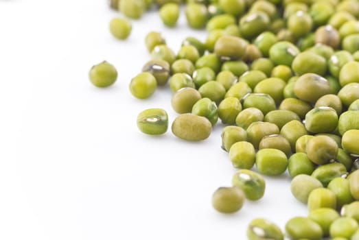 Macro (close-up) of green mung beans, scattered on right side of frame.  Isolated with white copy space to the left.  Horizontal (landscape) orientation.