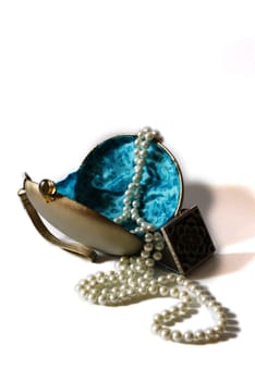 Lady's bag with mirror and pearls isolated on white background