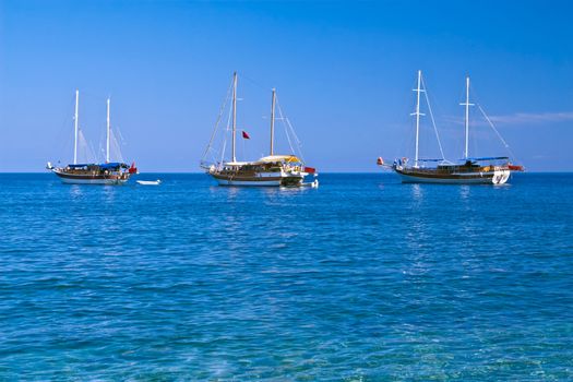 Three sailboats with lowered sails in sunny weather, with copyspace