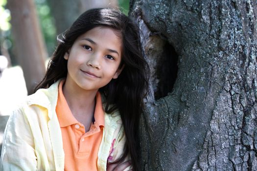 Young girl relaxing against tree in summer. Part Thai - Scandinavian descent