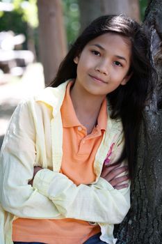 Young girl relaxing against tree in summer. Part Thai - Scandinavian descent