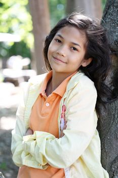 Young girl relaxing against tree in summer. Part Thai - Scandinavian descent