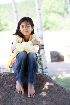 Little girl sitting under birch trees