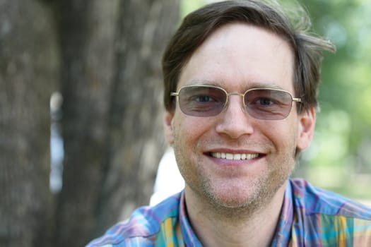 Smiling man enjoying outdoors in summer, wearing sunglasses