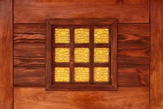 Yellow decorative stained-glass window in the reddish lacquered wooden frame