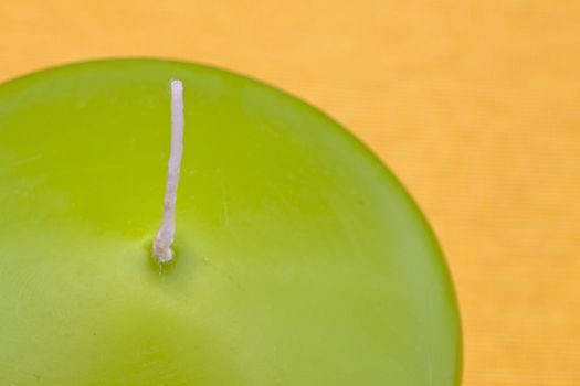 Green unlit candle on yellow background