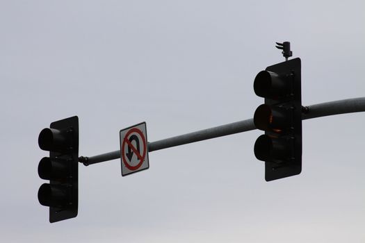 Traffic lights and a traffic sign over blue sky.