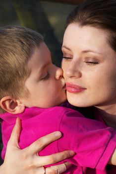 Closeup portrait of a preschool boy kissing his mother