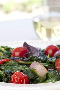 Warm spinach salad with cherry tomatoes and red onions.