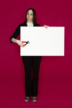 Young business woman holding a pair of pliers pointing to a white board  against pink background