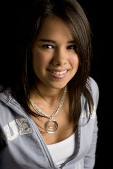 Teen girl smiling against a black background