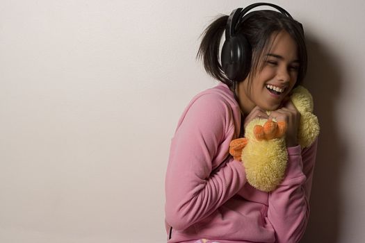 Teenage girl with black headphone hugging a plush toy