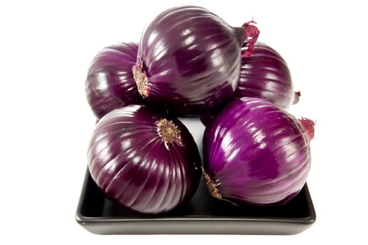 Picture of a bunch of red onions on a black plate