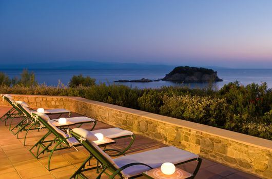 Evening picture of deckchairs on Greek verandah for people to experience the sea view 