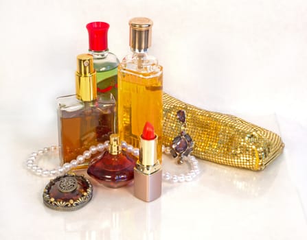 An assortment of vintage perfume and cosmetics with a strand of pearls.