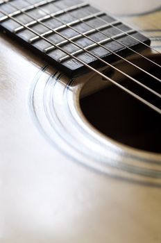 Close up view of the strings and body of an acoustic guitar.